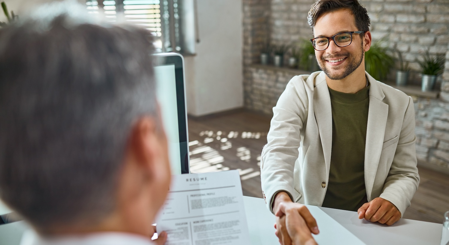 Young happy man shaking hands with a businessman on a job interview in the office.